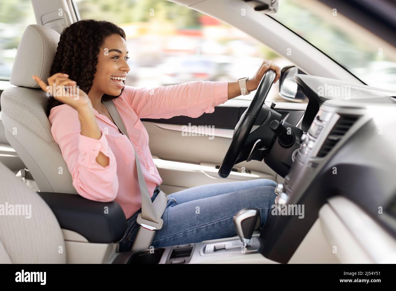 Felice donna nera godendo la musica che guida auto di lusso Foto Stock