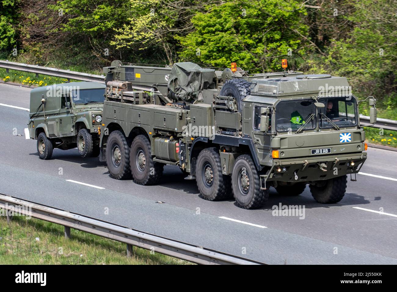 Green British Army militari MAN Trucks; HX 8x8 Heavy Recovery veicoli che trainano Land Rover viaggiando sull'autostrada M6, Regno Unito Foto Stock