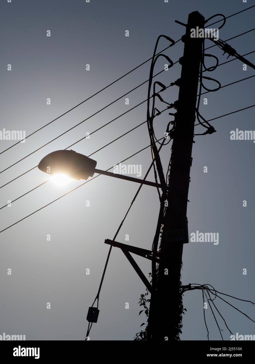 Qui vediamo palo che porta una luce di strada e cavi assortiti sulla mia passeggiata attraverso Lower Radley fino al Tamigi; è tutto illuminato da una sorgente luminosa Foto Stock