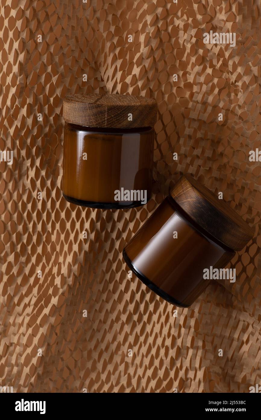 Contenitore per cosmetici e creme. Vaso marrone in vetro con coperchio in legno. Sfondo beige. Concetto monocromatico. Posizionare un'etichetta. Vasetti di crema. Bellezza e cura. Minimalismo Foto Stock