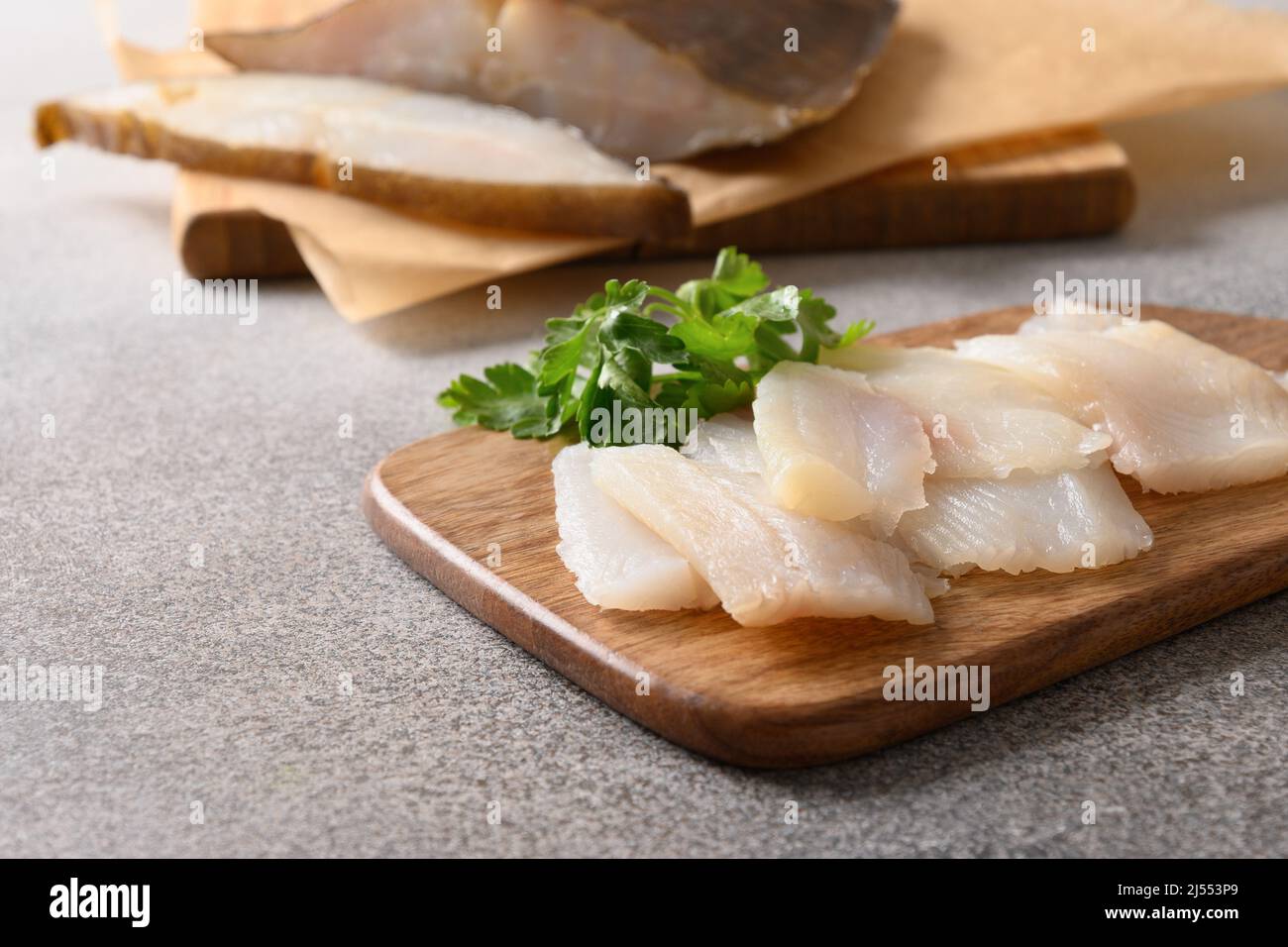 Pesce prelibato halibut affumicato servito con prezzemolo per mangiare sul tagliere di legno. Primo piano. Ricco di grassi sani omega 3 insaturi. Foto Stock