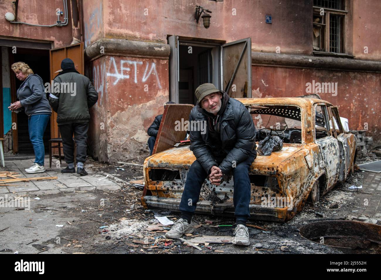 Mariupol, Ucraina. 15th Apr 2022. Un uomo riposa su un'auto bruciata in un quartiere in rovina di Mariupol vicino alle linee di frontiera nella parte orientale della città. La battaglia tra le forze russe/Pro russe e le forze ucraine in difesa guidate dal battaglione Azov continua nella città portuale di Mariupol. (Foto di Maximilian Clarke/SOPA Images/Sipa USA) Credit: Sipa USA/Alamy Live News Foto Stock