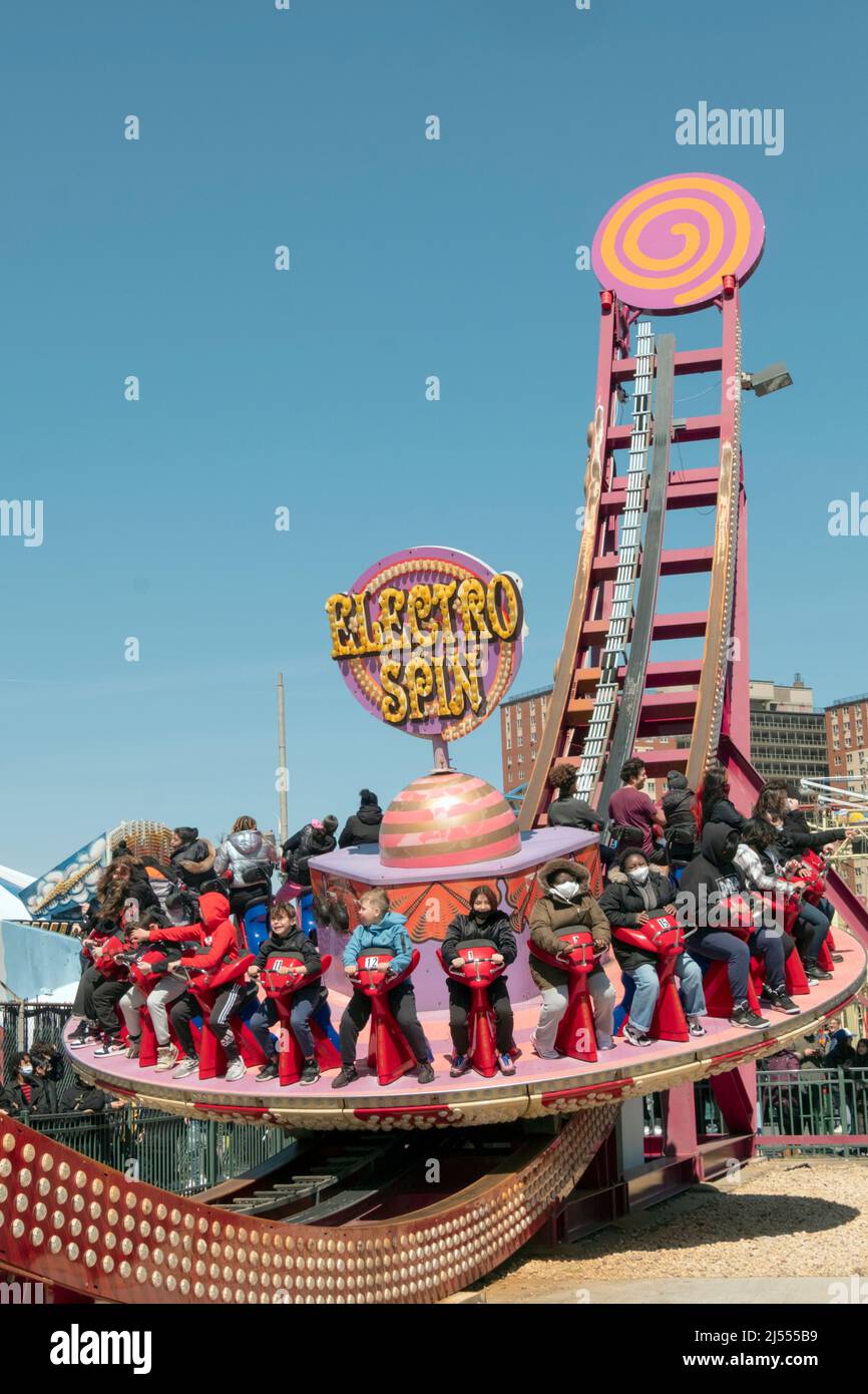 I giovani uomini e le donne si divertiranno con la corsa Electro Spin a Luna Park nei primi giorni primaverili. Coney Island, Brooklyn, New York, 2022. Foto Stock