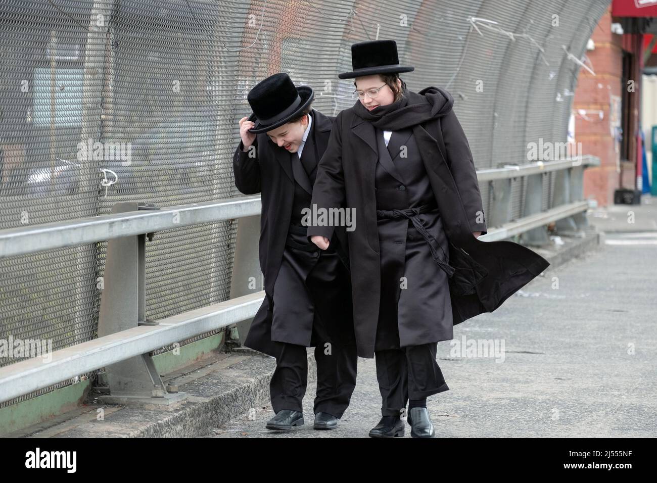 Due giovani ebrei ultra ortodossi nei loro vestiti di festa, camminano su  Lee Avenue in una ventosa giornata di primavera. A Williamsburg, Brooklyn,  New York Foto stock - Alamy