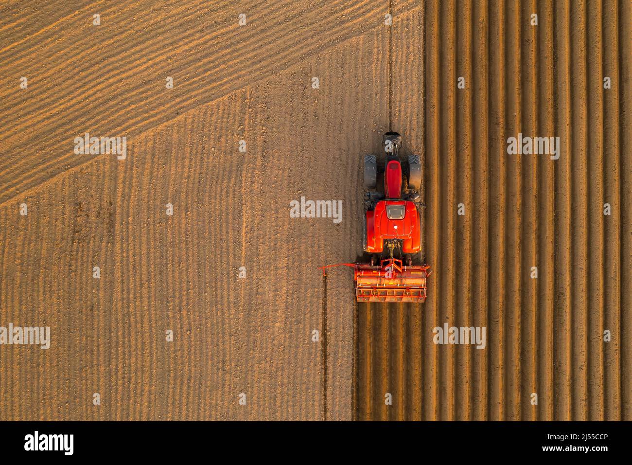 PRAGA , REPUBBLICA CECA - MARZO 18 2022: Trattori guidano preparando letti per piantare piantine in terreno coltivato. La macchina pesante si dissoda sul campo aiutandoti con la vista aerea dell'agricoltura Foto Stock
