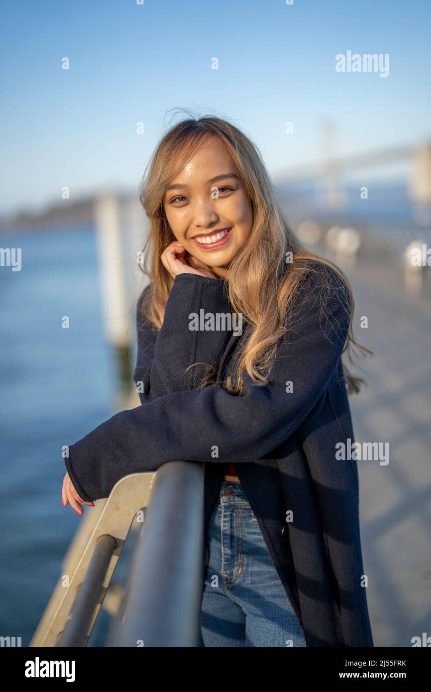 Felice giovane donna che si appoggia sul ringhiera di un molo a San Francisco | Lifestyle Turismo locale Foto Stock