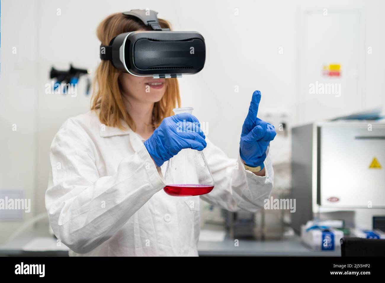 Scienziato che indossa occhiali VR, camice da laboratorio, fiasca per giocare nel cyberspazio digitale metaverse con la realtà virtuale. Tecnologia NFT di intrattenimento futuro. Foto Stock