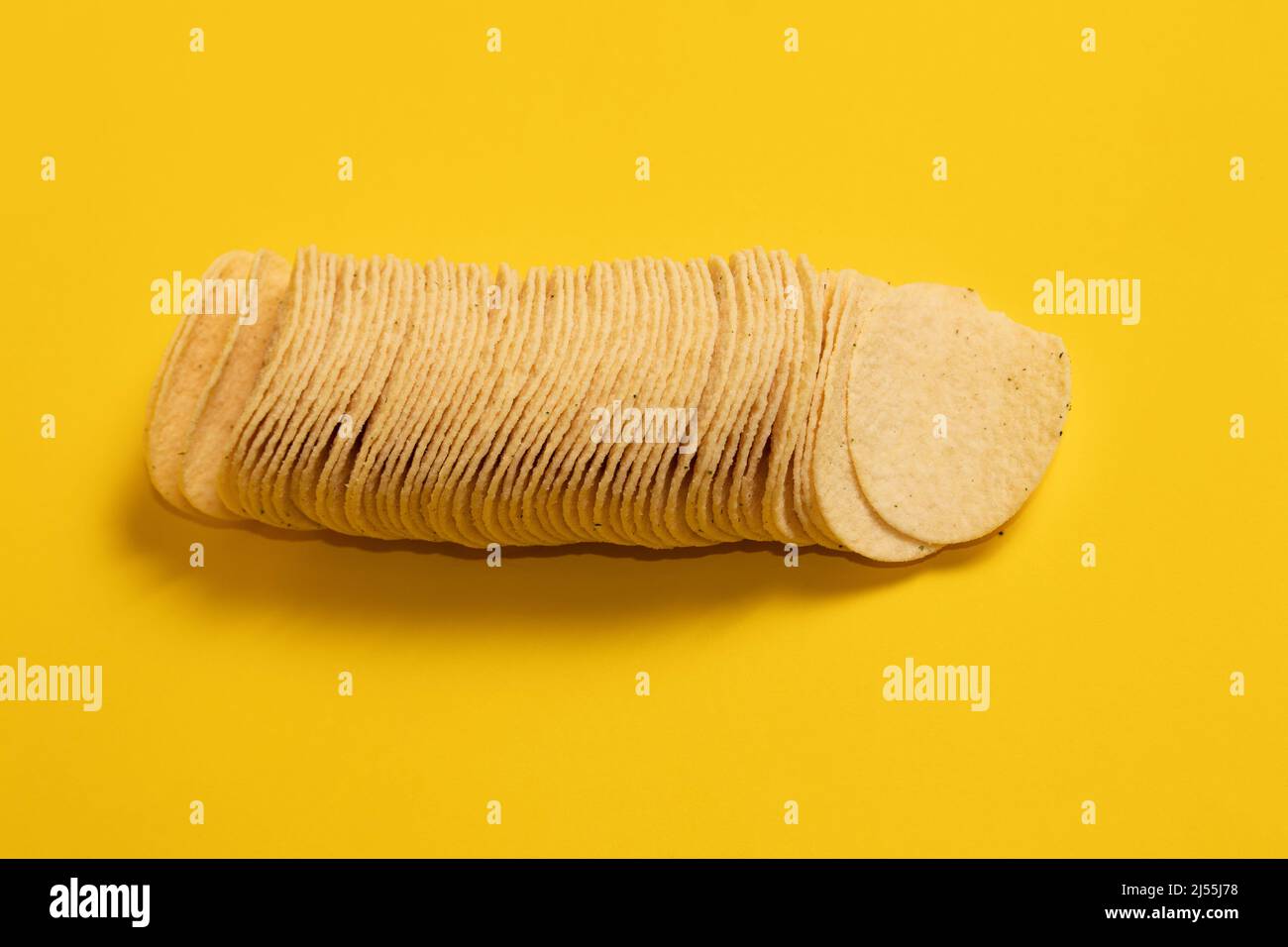 Pila di patatine su sfondo giallo Foto Stock