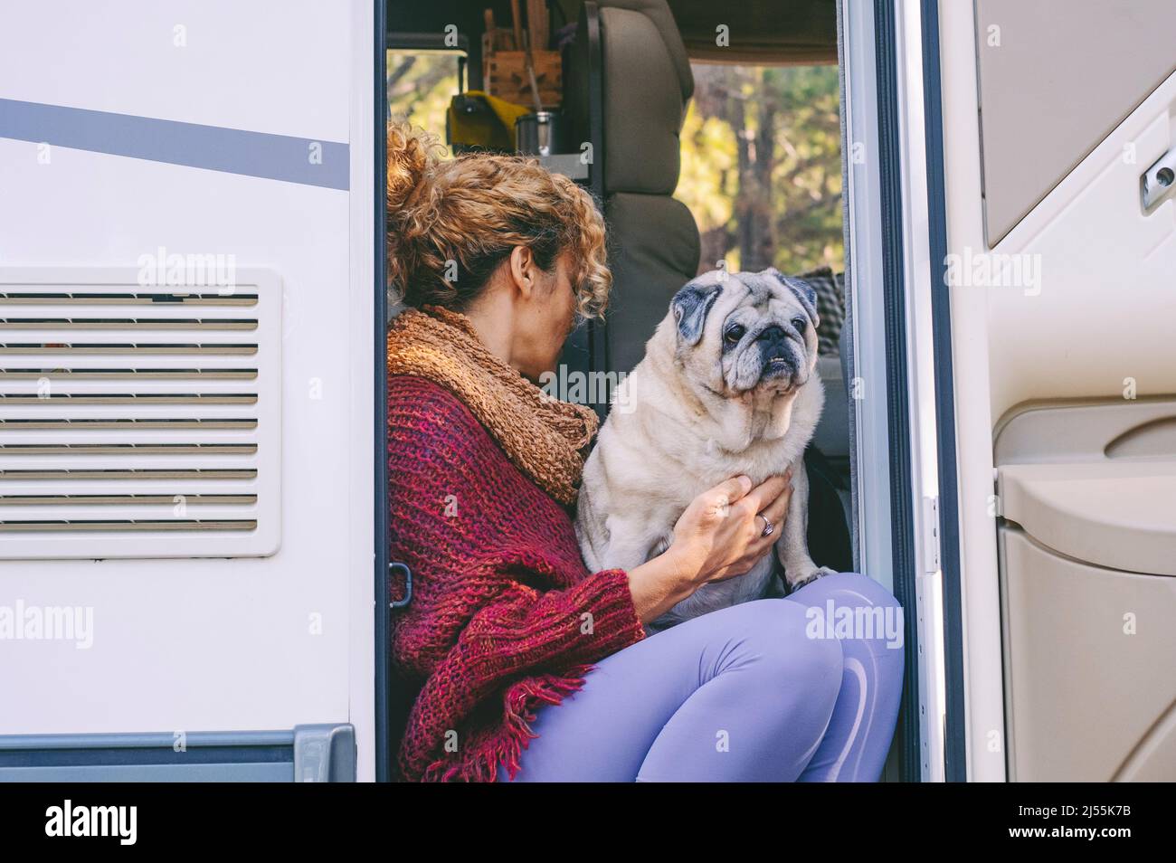 Vivere fuori stile di vita griglia con la donna e il suo cane migliore amico seduto e rilassante sulla porta della moderna camper a motore casa. Peo di vanlife alternativo Foto Stock