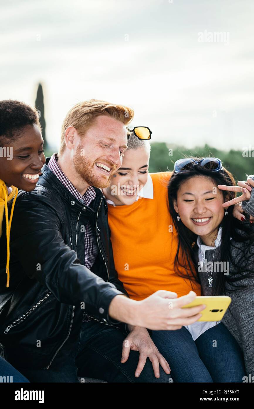 Felice gruppo millenario di persone multirazziali che prendono insieme selfie all'aperto Foto Stock