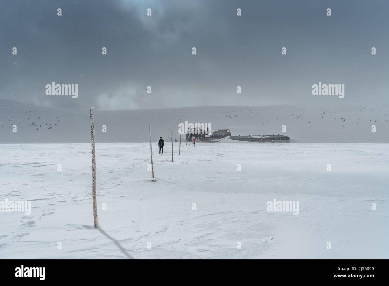 Sport uomo escursioni a Krkonose, repubblica Ceca, nuvoloso giorno d'inverno, caduta neve flakes.Tourist con zaino, panorama di montagna e chalet.Adventure Foto Stock