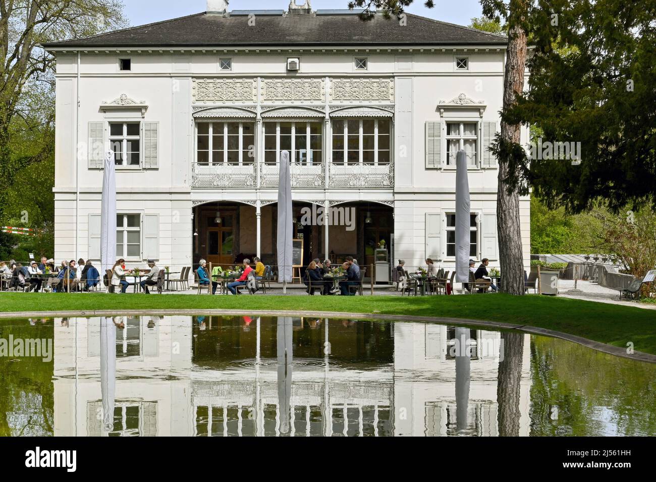 Basilea, Svizzera - Aprile 2022: Persone al caffè sul retro della Villa Merian nei Giardini Meriani, un giardino botanico vicino al centro della città Foto Stock