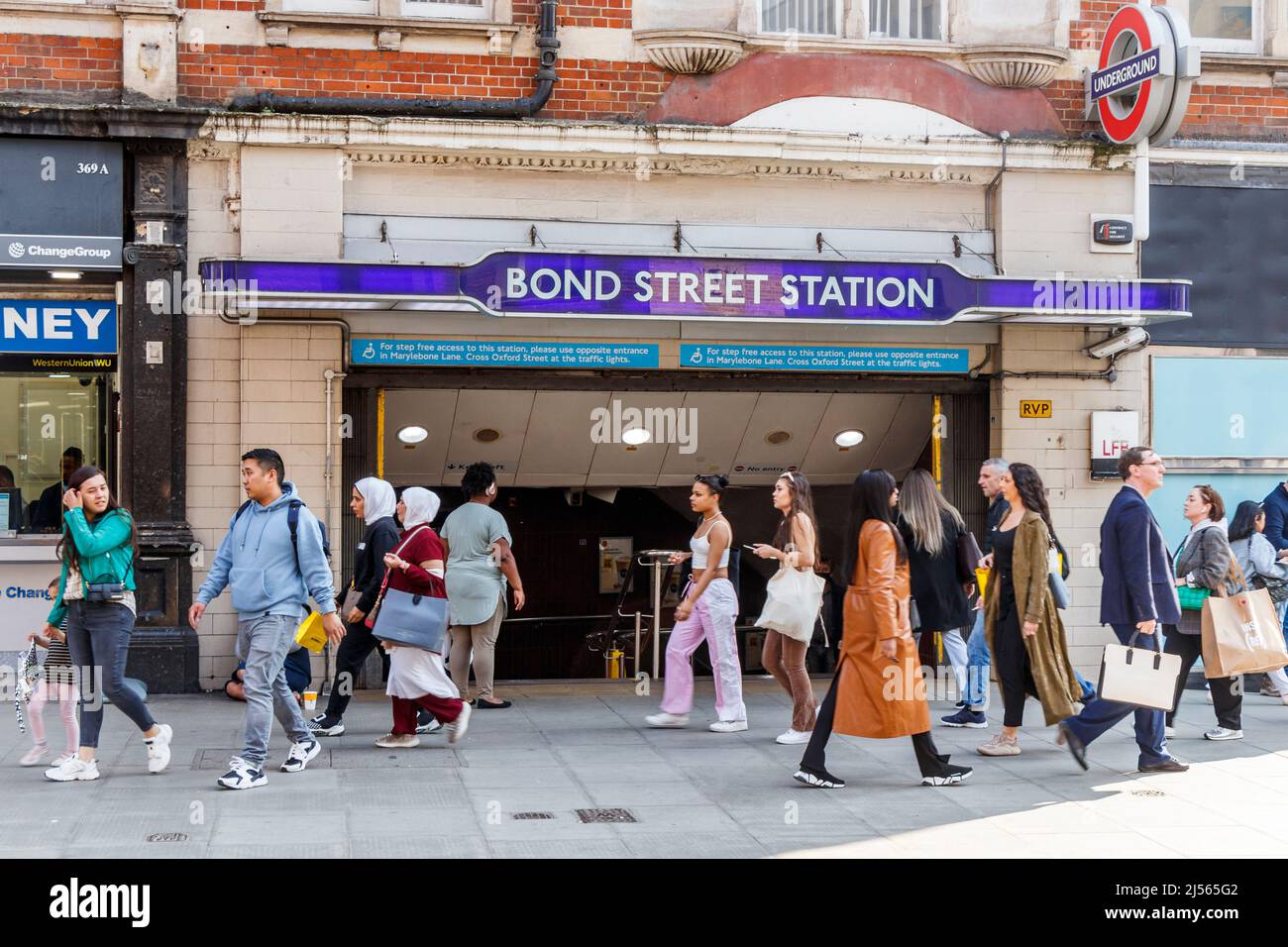 Pedoni e pendolari fuori dalla stazione della metropolitana di Bond Street a Oxford Street, Londra, Regno Unito Foto Stock