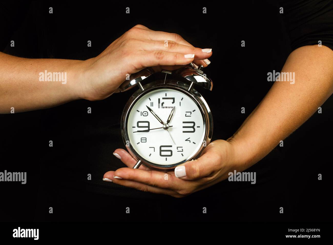 Donna che tiene una sveglia con entrambe le mani Foto Stock