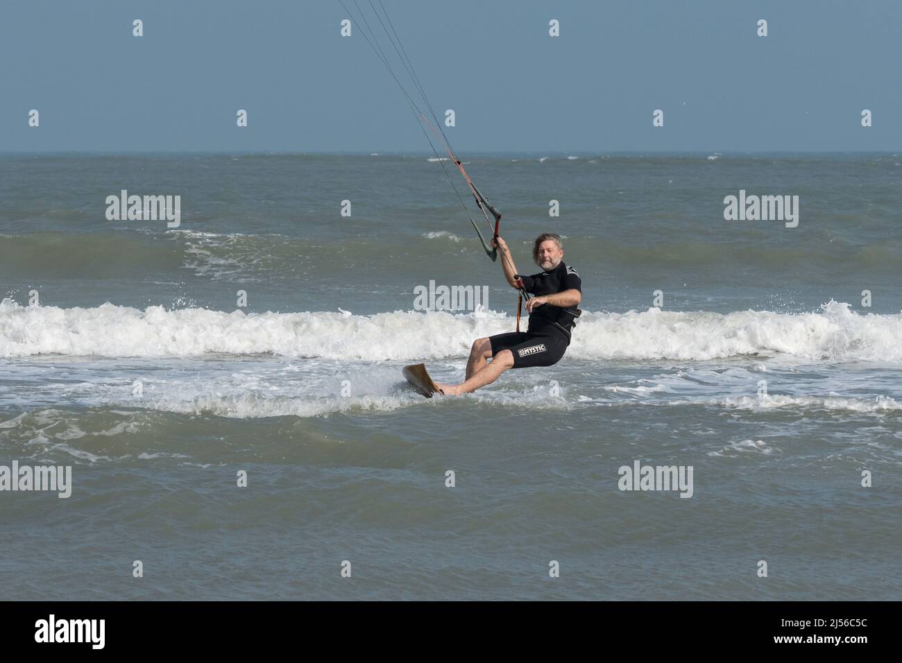Un kite surfer su una tavola da surf in legno taglia attraverso il surf mentre si kiting nel Golfo del Messico a South Padre Island, Texas. Foto Stock