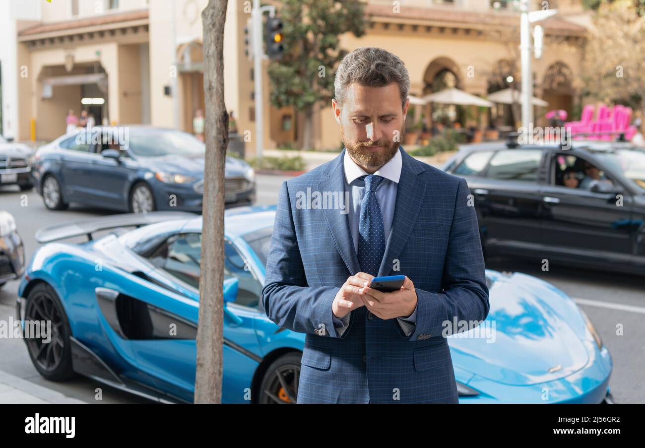 l'uomo del concessionario chiacchiera sullo smartphone accanto all'auto. spazio di copia Foto Stock