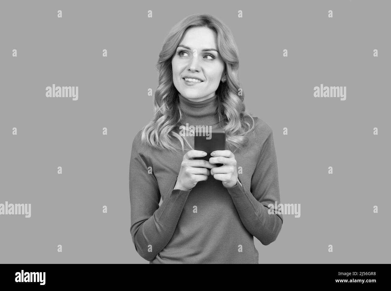 Bella ragazza in stile casual SMS breve messaggio sul cellulare smart dispositivo sfondo grigio, sms Foto Stock