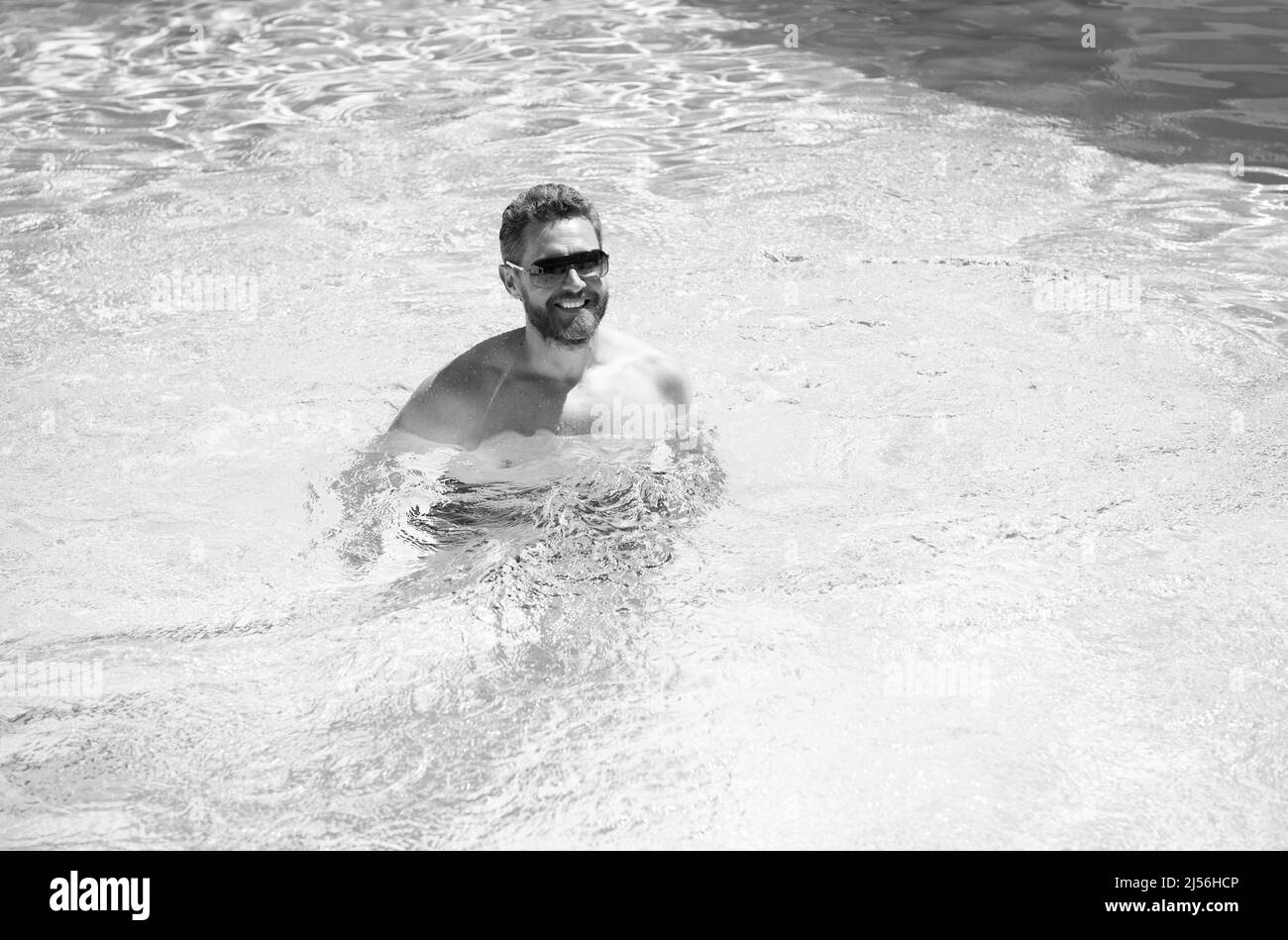 felice uomo con gli occhiali da sole godetevi relax nella piscina del resort termale durante le vacanze estive, in estate. Foto Stock