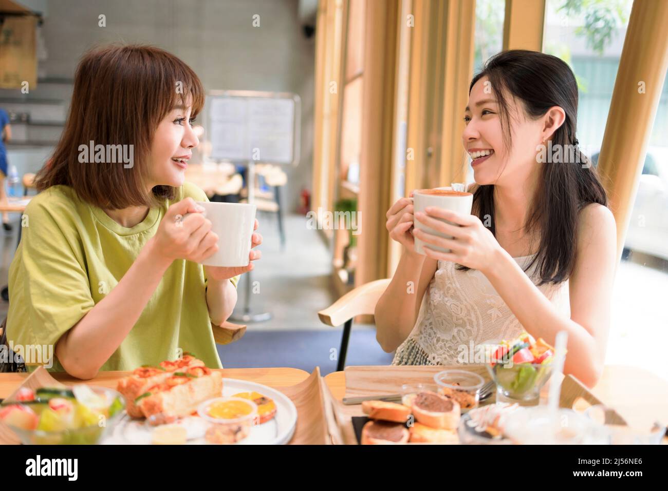 Buone donne giovani che bevono caffè in caffetteria Foto Stock