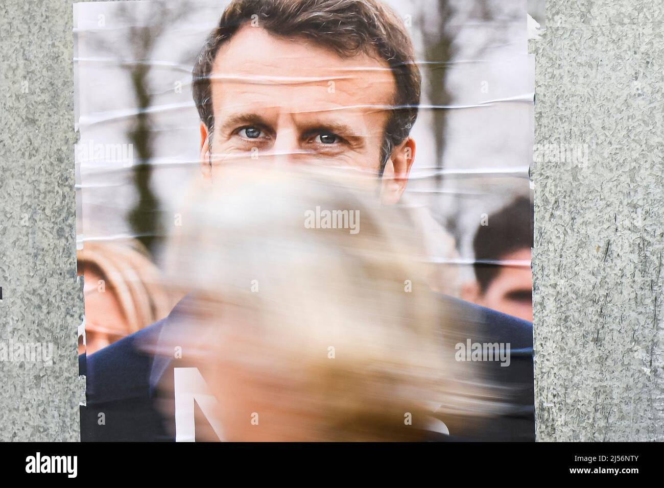 Parigi, Francia, 20 aprile 2022, Un pedone trasmette poster ufficiali della campagna su un cartellone elettorale (cartello). Poster presidenziali sui loro consigli elettorali. Illustrazione del 20 aprile 2022 a Parigi, Francia. Gli elettori francesi si dirigono ai sondaggi per votare il 24 aprile 2022 per il secondo turno delle elezioni presidenziali, per eleggere il loro nuovo presidente della Repubblica tra Emmanuel Macron e Marine le Pen. Foto Stock