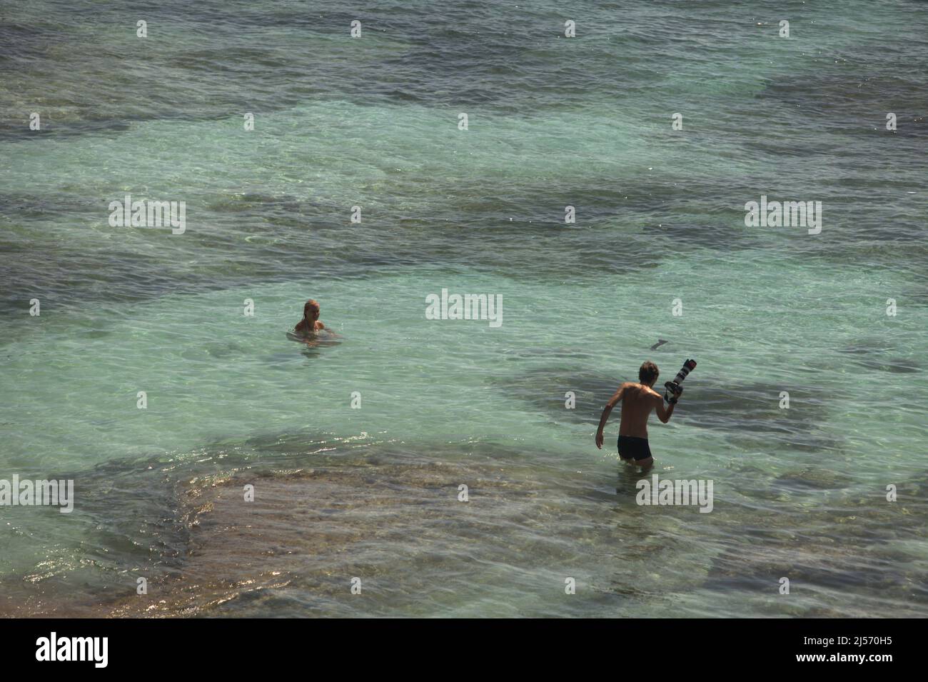 Un fotografo sta per scattare foto di una donna sulla spiaggia di Padang-padang a Labuan Sait, South Kuta, Badung, Bali, Indonesia. Secondo Trip Advisor, Bali è stata la quarta destinazione più popolare del mondo in epoca pre-Covid. L'ufficio delle statistiche della provincia di Bali aveva menzionato che 6.275.210 turisti visitarono Bali nel 2019, il suo record più alto. Tuttavia, solo 1.069.473 visitarono l'Isola degli dei nel 2020 a causa della pandemia, seguita da appena 51 (calo del 100%) nel 2021. Foto Stock