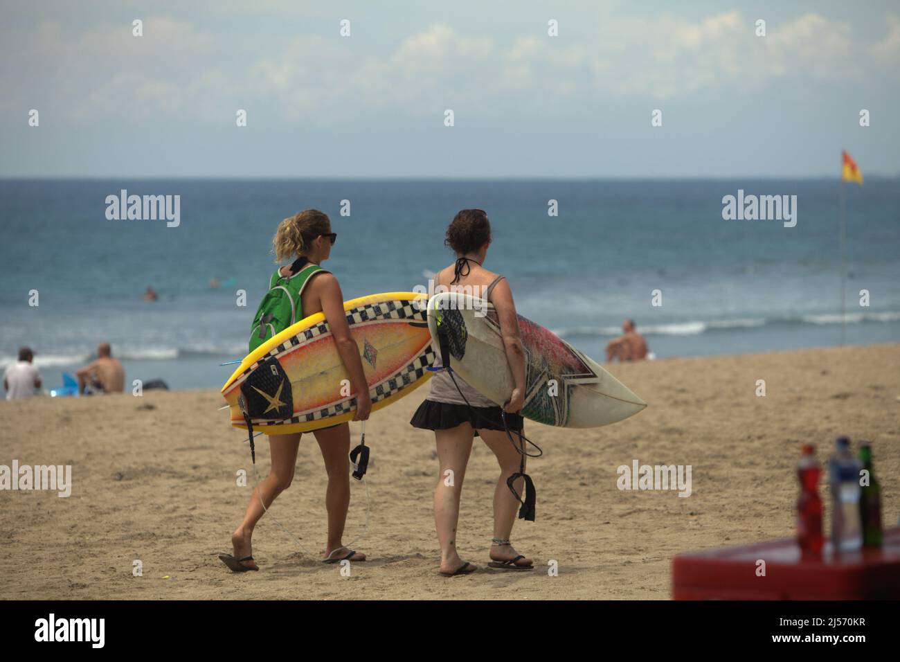 Le donne e i turisti trasportano tavole da surf, mentre camminano sulla spiaggia di Kuta, Badung, Bali, Indonesia. Secondo Trip Advisor, Bali è stata la quarta destinazione più popolare al mondo nel periodo pre-Covid. L'ufficio di statistica della provincia di Bali ha menzionato che 6.275.210 turisti hanno visitato Bali nel 2019, il suo record più alto. Tuttavia, solo 1.069.473 hanno visitato l'Isola degli dei nel 2020 a causa della pandemia, seguita da solo 51 (calo del 100%) nel 2021. Foto Stock