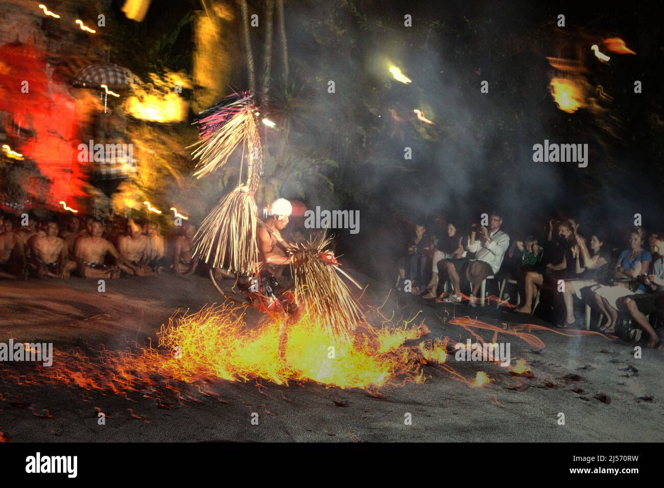 Un interprete di danza del fuoco corre su una pila di noci di cocco in fiamme di fronte ai turisti, durante lo spettacolo di kecak e danza del fuoco a Ubud, una delle principali destinazioni turistiche di Bali che si trova nella reggenza di Gianyar, Bali, Indonesia. Secondo Trip Advisor, Bali è stata la quarta destinazione più popolare al mondo nel periodo pre-Covid. L'ufficio di statistica della provincia di Bali ha menzionato che 6.275.210 turisti hanno visitato Bali nel 2019, il suo record più alto. Tuttavia, solo 1.069.473 hanno visitato l'Isola degli dei nel 2020 a causa della pandemia, seguita da solo 51 (calo del 100%) nel 2021. Foto Stock