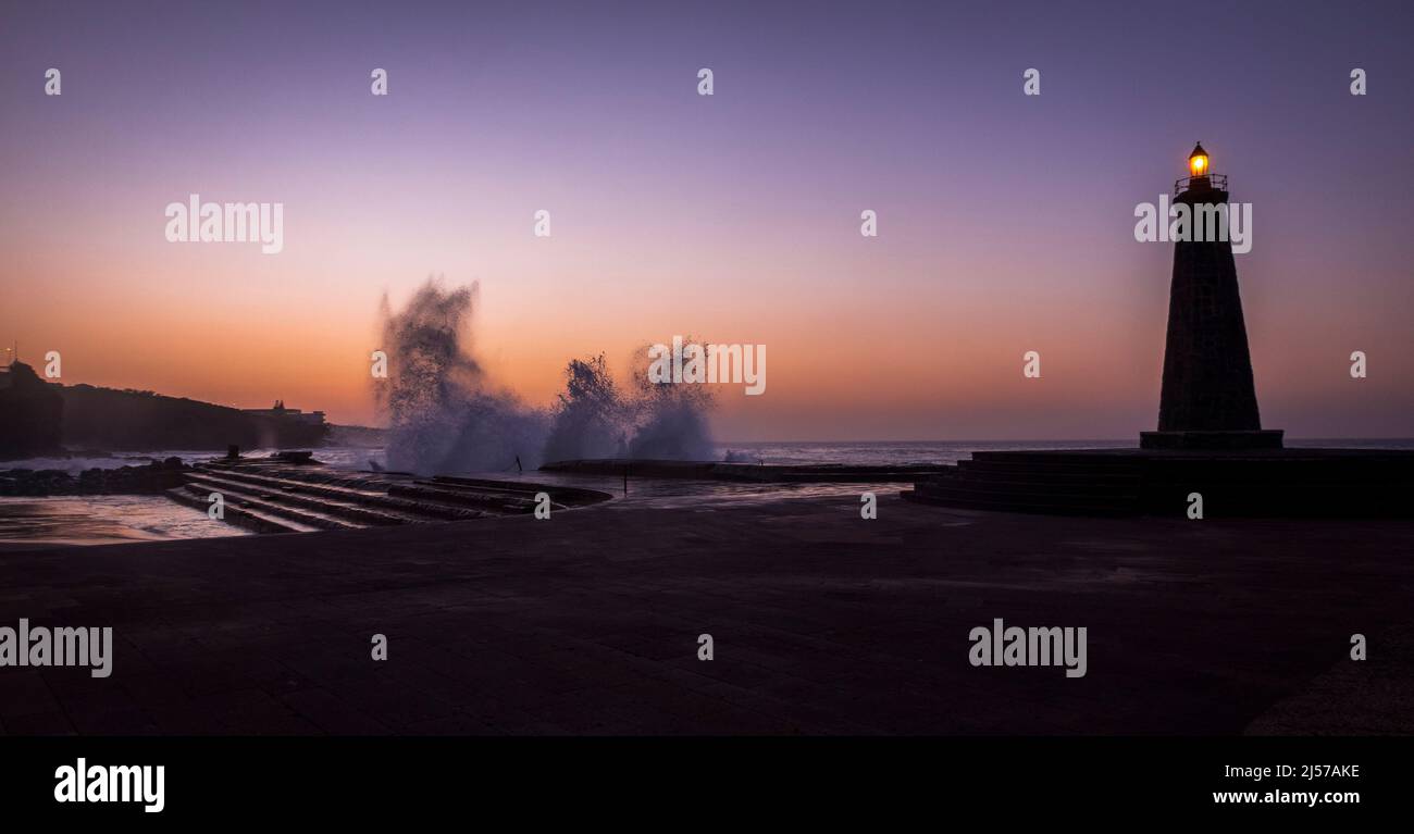 Onde che si infrangono sui gradini della piscina di mare naturale al tramonto a Bajamar, a nord delle Isole Canarie di Tenerife Foto Stock