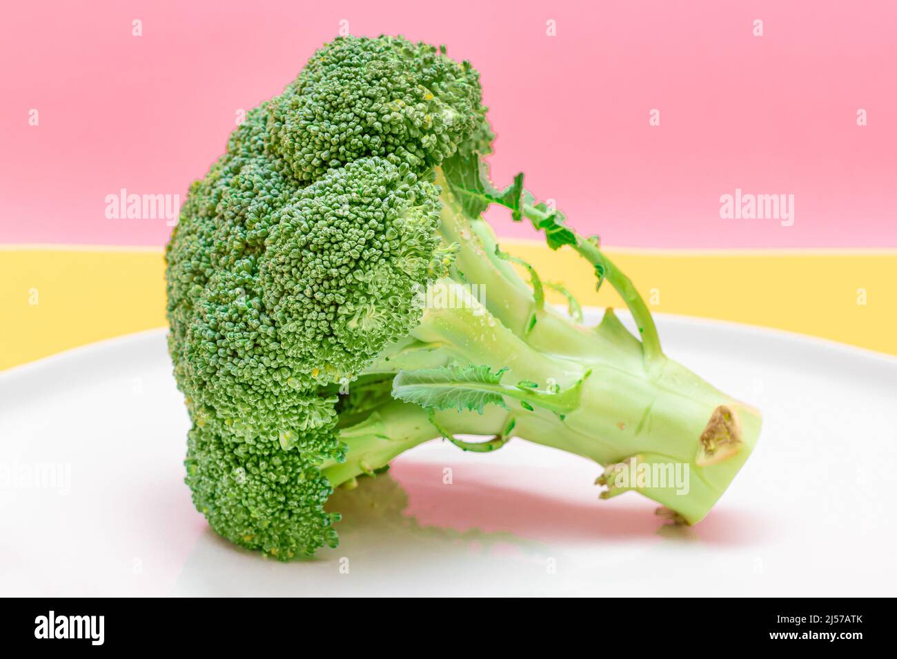 Broccoli freschi e crudi su piatto bianco. Cavolo verde non fatto. Cultura vegana e vegetariana. Cibo crudo. Alimentazione sana e dieta vegetale Foto Stock