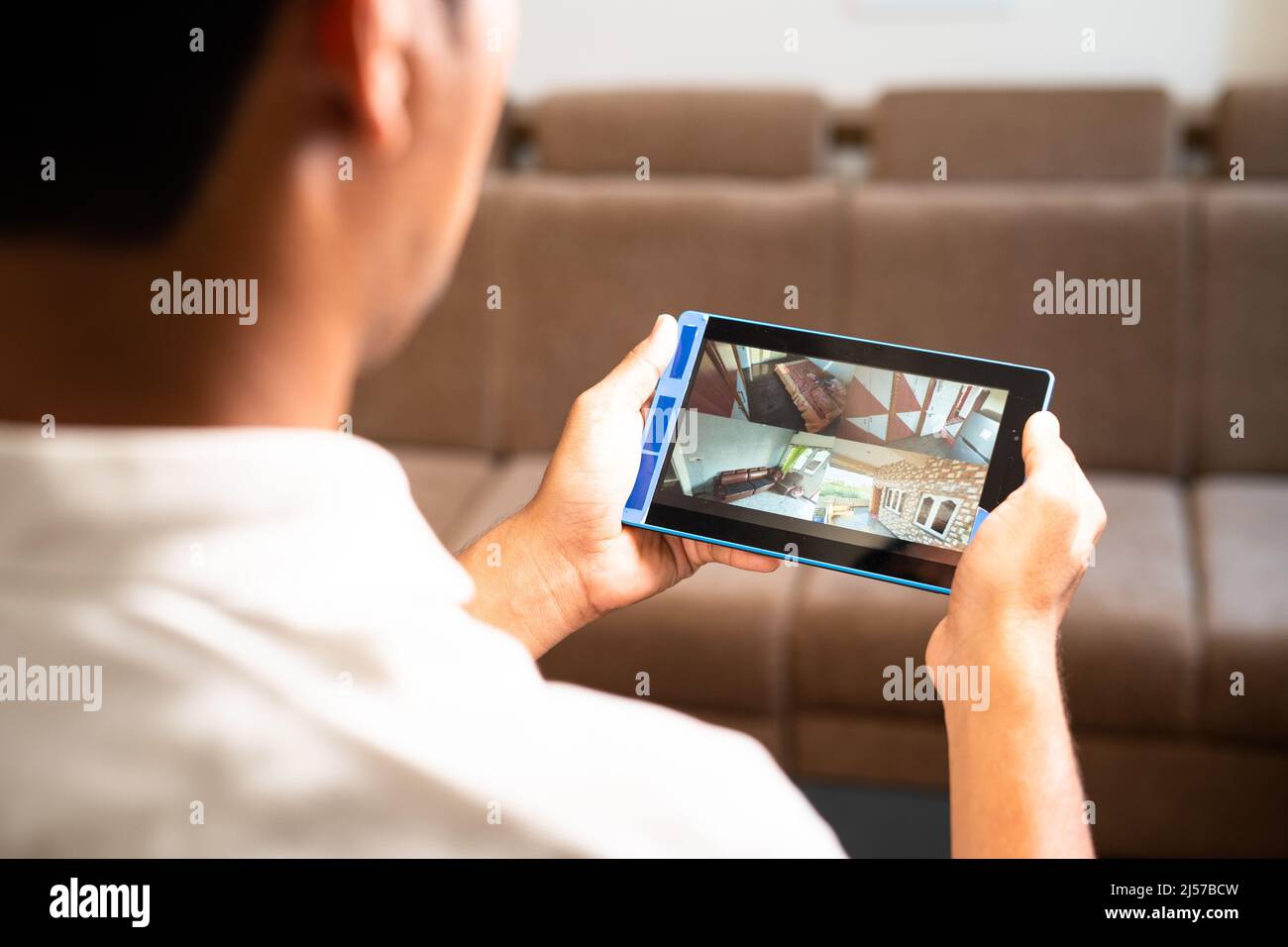 La spalla del proprietario di casa controlla le riprese della telecamera tvcc su tablet digitale intelligente a casa - concetto di sicurezza, tecnologia e sorveglianza. Foto Stock