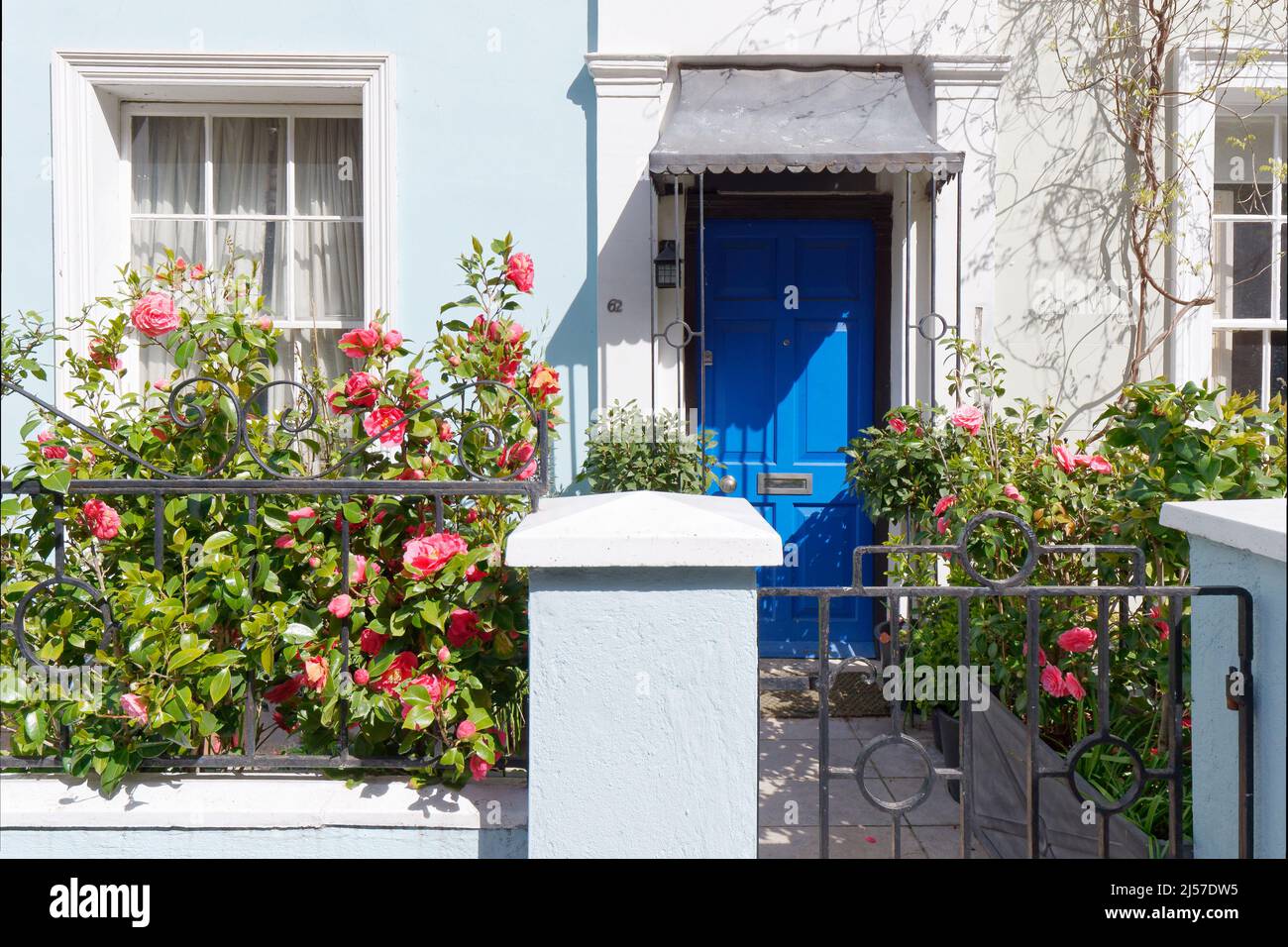 Molto caratteristico casa blu chiaro con porta blu scuro e rose rosse nel giardino di fronte. Portabello Road, Notting Hill, Londra. Foto Stock