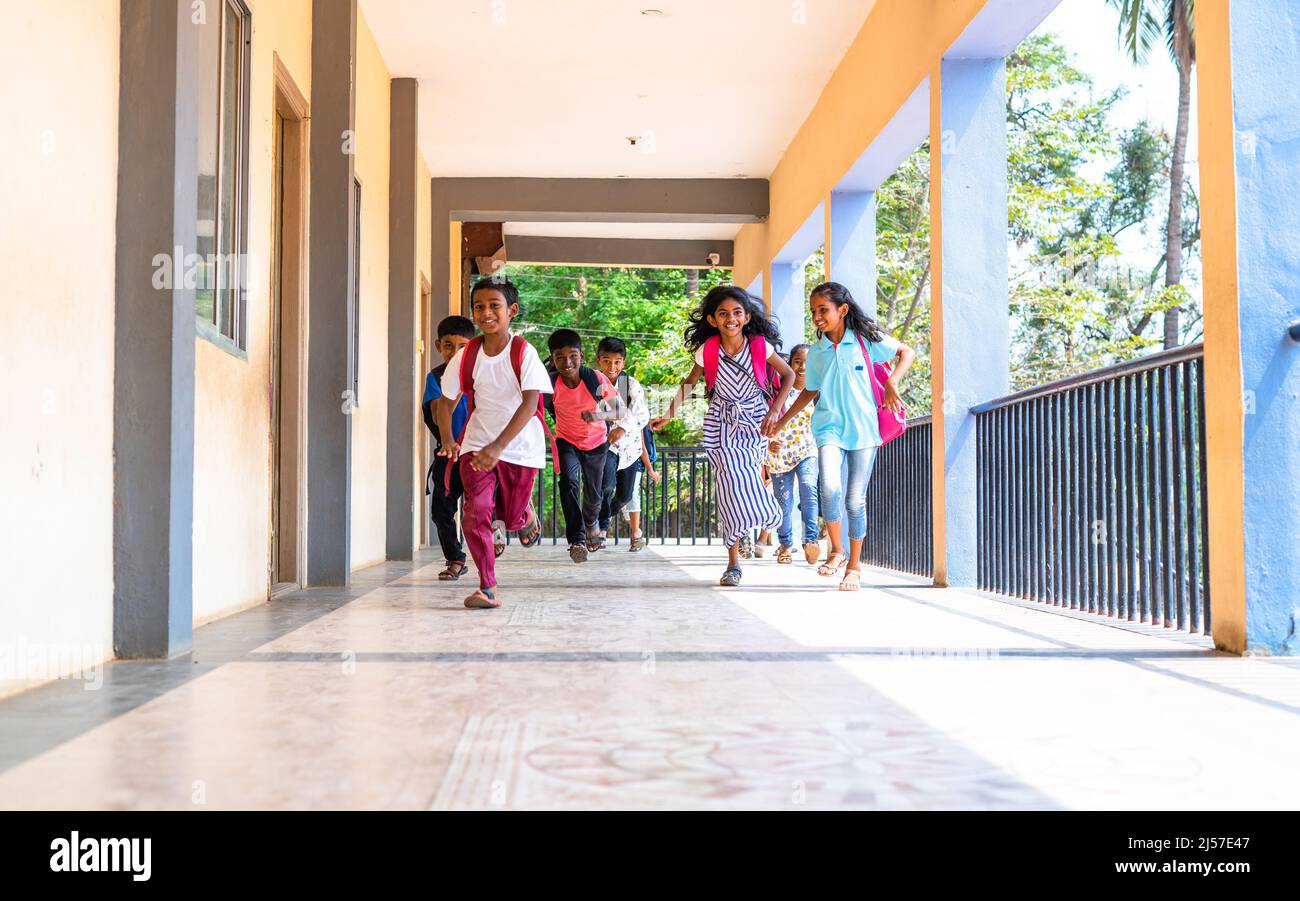 Un gruppo di bambini che corre nel corridoio della scuola per andare in classe - concetto di istruzione, riaprire la scuola, infanzia attiva e apprendimento. Foto Stock