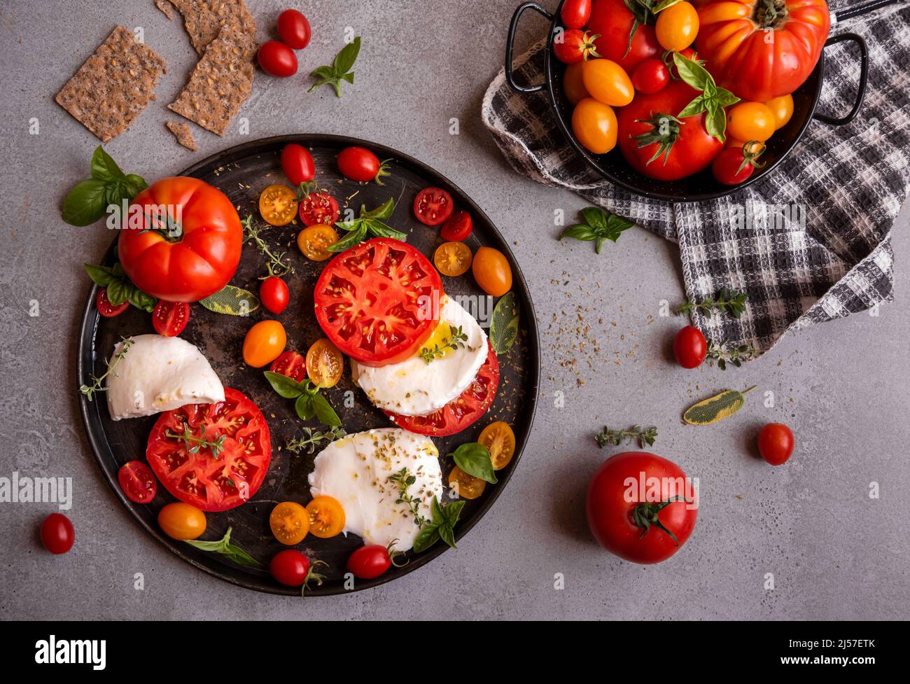Vari pomodori interi e tagliati serviti con basilico Foto Stock