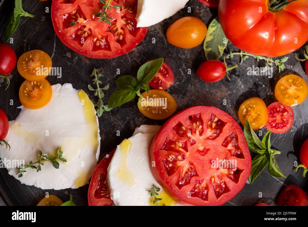 Vari pomodori interi e tagliati serviti con basilico Foto Stock