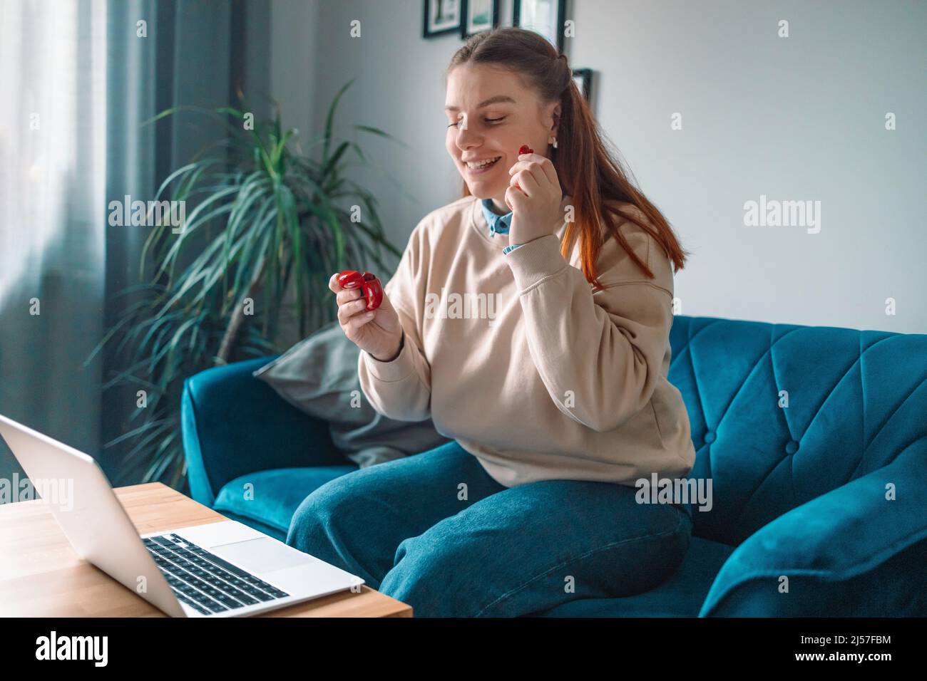 le mani della donna freelance con le cuffie senza fili rosse rimangono a casa seduta comodo soggiorno del divano all'interno Foto Stock
