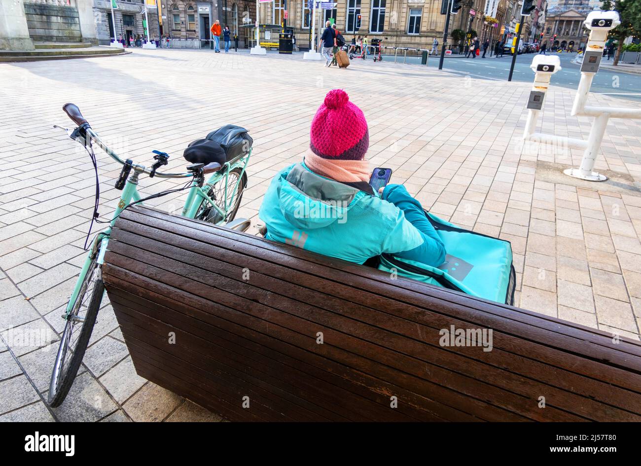 Black femmina addetto alla consegna della bicicletta che riposa e controlla le sue posizioni nel centro di Liverpool Foto Stock