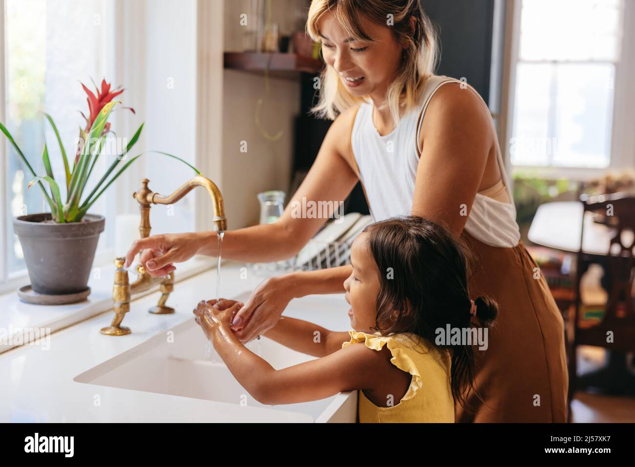 Madre insegnando a sua figlia di lavarsi le mani con sapone e acqua corrente. Mamma amorevole seguendo le misure precauzionali a casa. Madre e figlia s Foto Stock