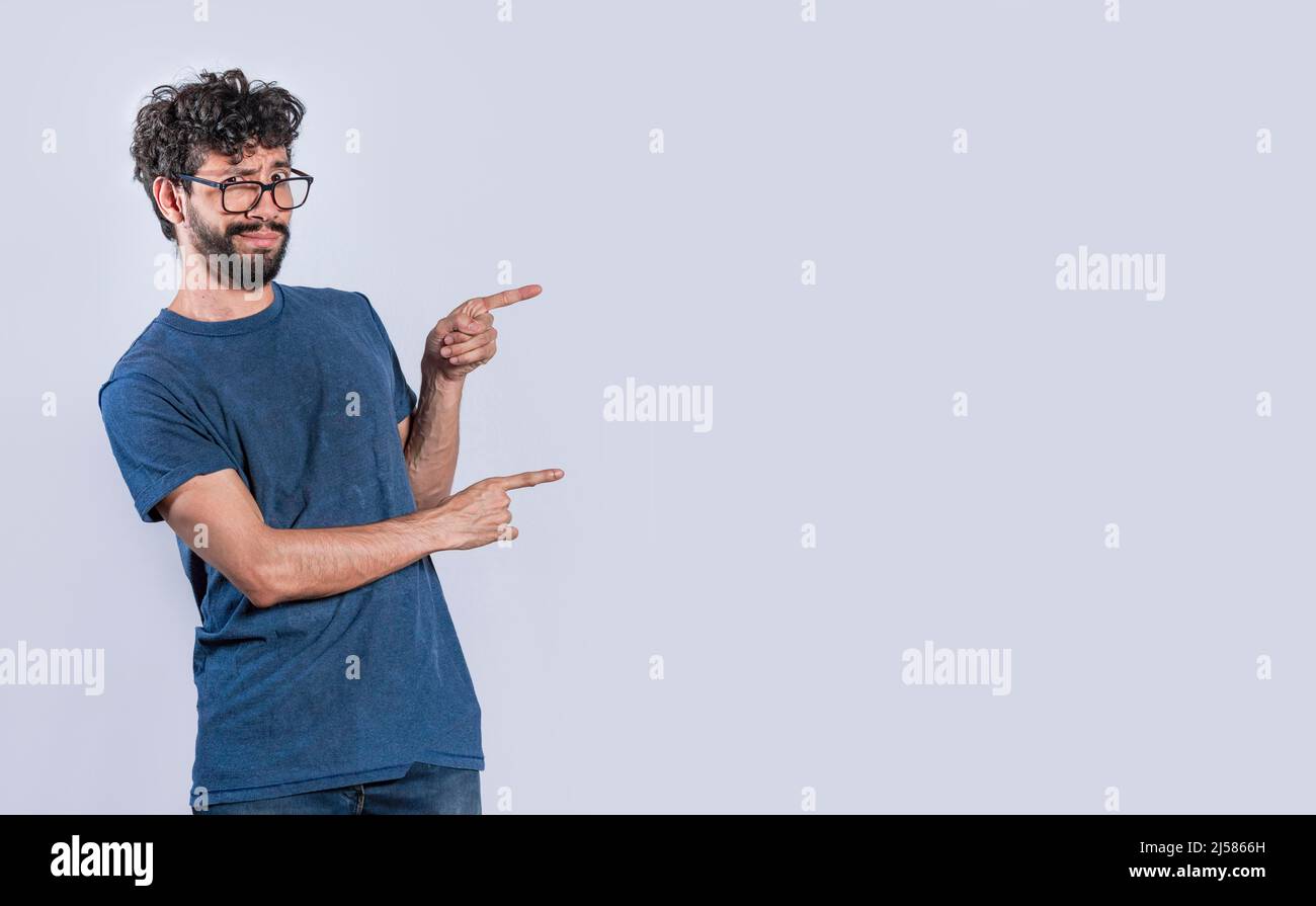 Bell'uomo che punta al lato, ragazzo amichevole che punta le dita al lato, giovane uomo che punta allo spazio vuoto Foto Stock