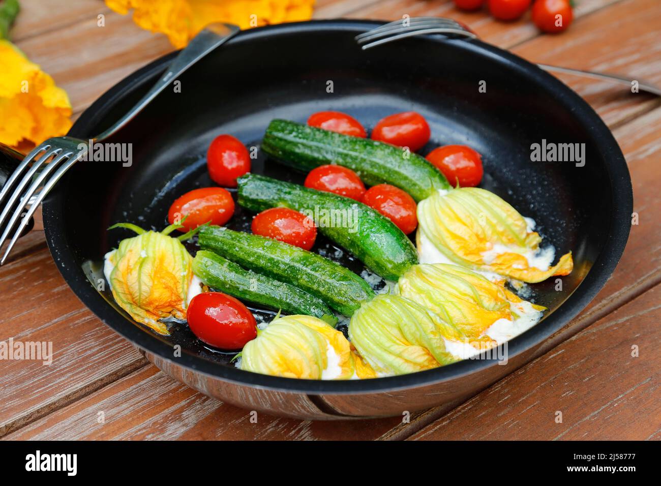 Cucina tedesca del sud, fiori di zucchine ripiene saltati in padella, formaggio spalmabile, pomodori da cocktail, pomodori ciliegini, vegetariano, cucina sana Foto Stock