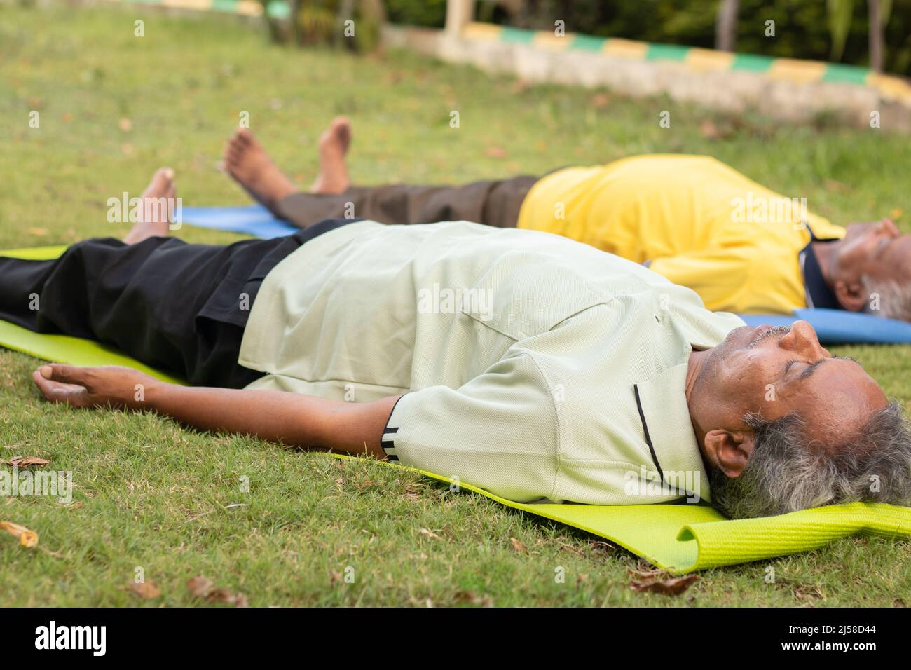 Full shot di vecchi uomini che praticano Shavasana o corpo posa alla fine di una classe - concetto di yoga per le persone anziane, attivo sano stile di vita anziano Foto Stock