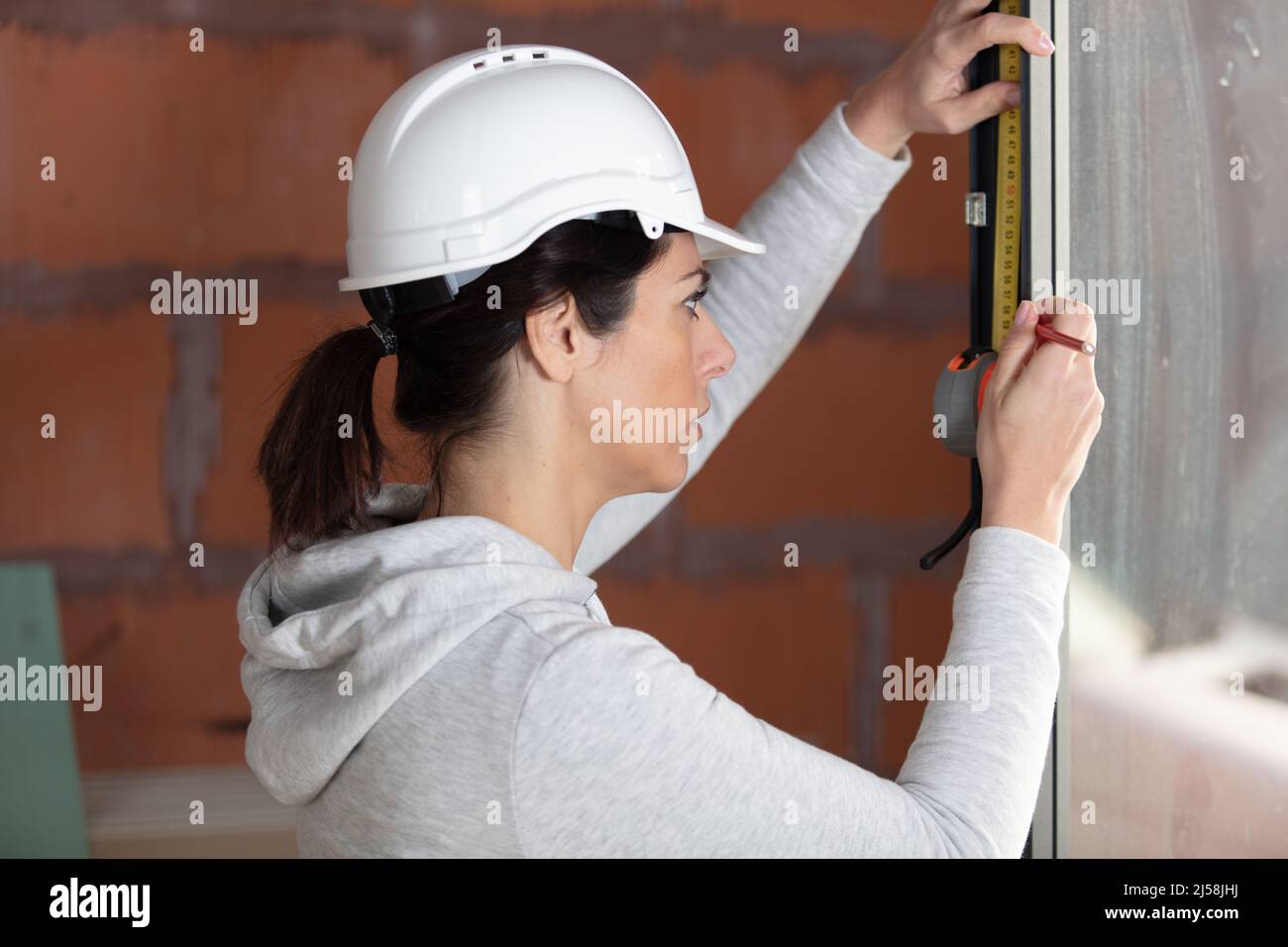 costruttore femminile che usa il livello dello spirito sulla finestra di newbuild Foto Stock
