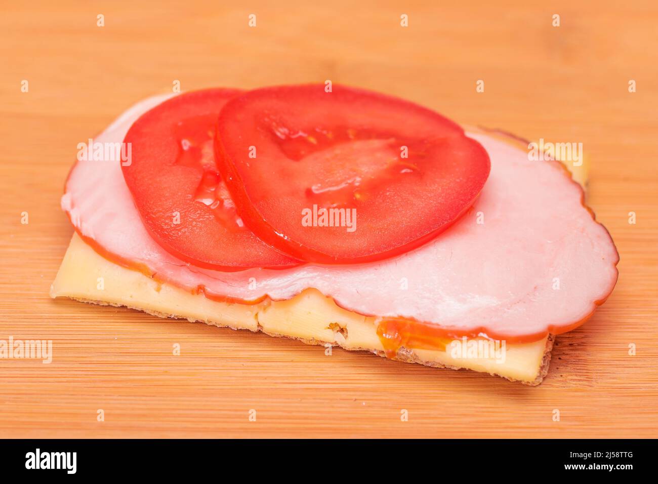 Crospead di grano intero con pomodoro, Pram e formaggio sul tagliere di bambù. Colazione facile. Panini veloci e sani. Croccante con gustoso ripieno. Snack dietetico sano Foto Stock