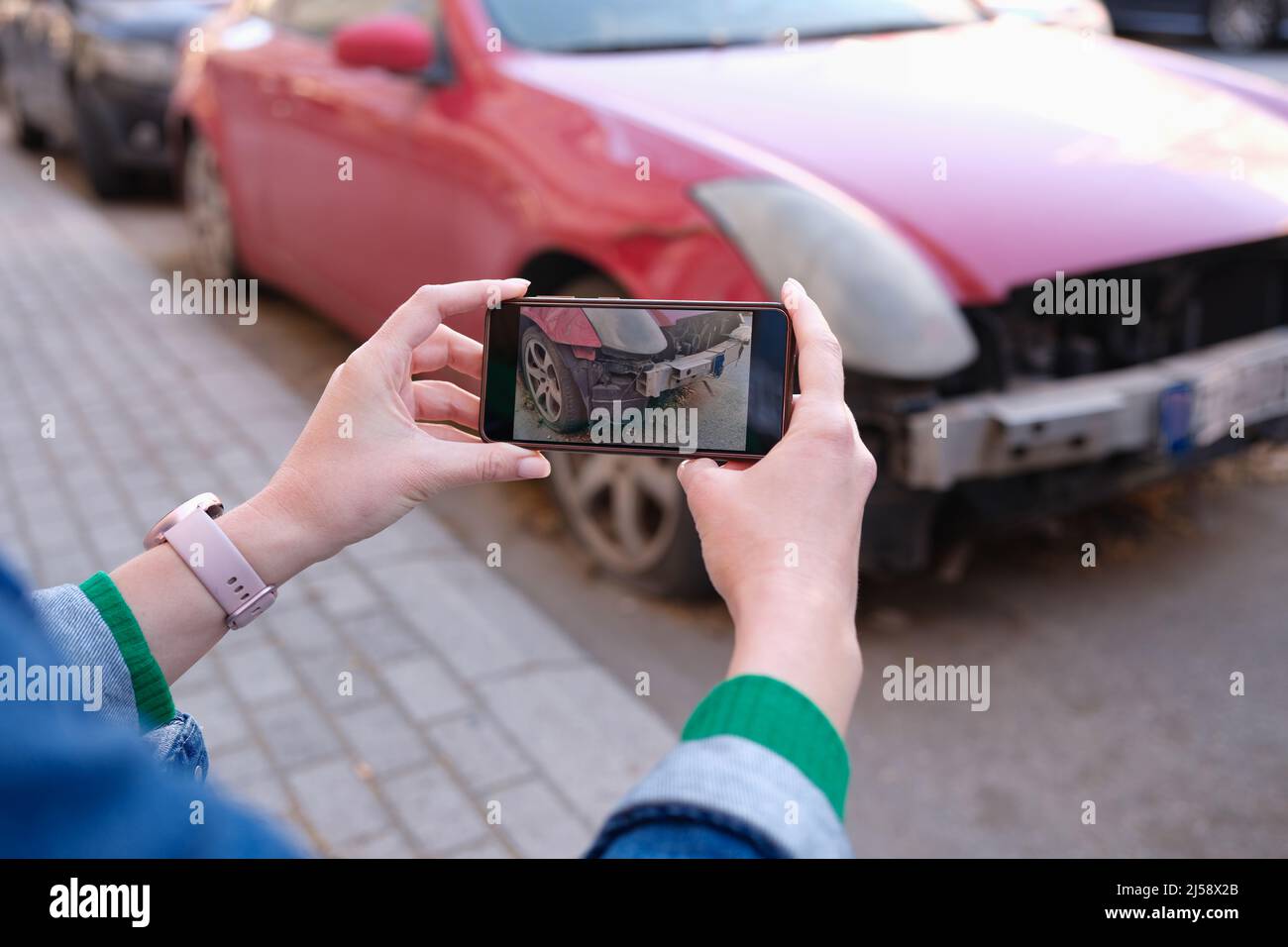 Le mani femminili scattano le foto dei danni dell'automobile sul primo piano del telefono mobile Foto Stock