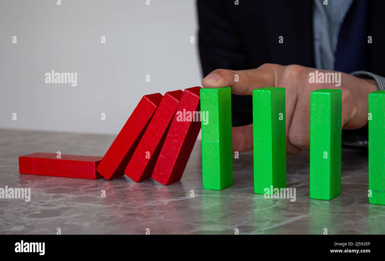 L'uomo d'affari sta bloccando la caduta dei blocchi di legno. Concetto di gestione delle crisi. Trovare la soluzione al problema. Strategia per il business. Foto Stock