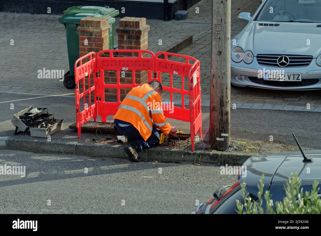 Un ingegnere di comunicazione BT Openreach che lavora su una linea telefonica in una strada suburbana Surrey Inghilterra Regno Unito Foto Stock