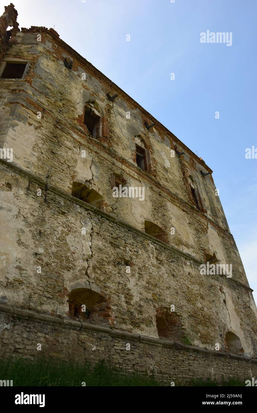 L'alto muro di una vecchia fortezza in pietra con scappatoie e scappatoie con rivestimento incrinato Foto Stock