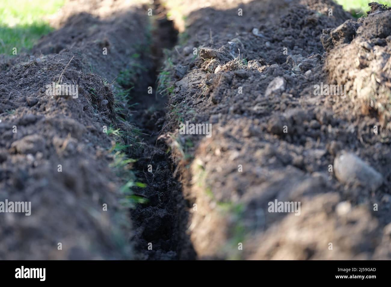 Trincea scavata in prato per la posa in primo piano del sistema di irrigazione Foto Stock