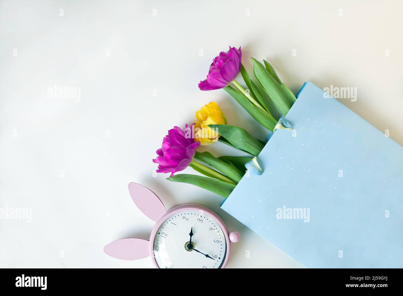 tulipano fiori, carta regalo e orologio rosa coniglietto in stile piatto. Saluto per il giorno delle donne o delle madri Foto Stock