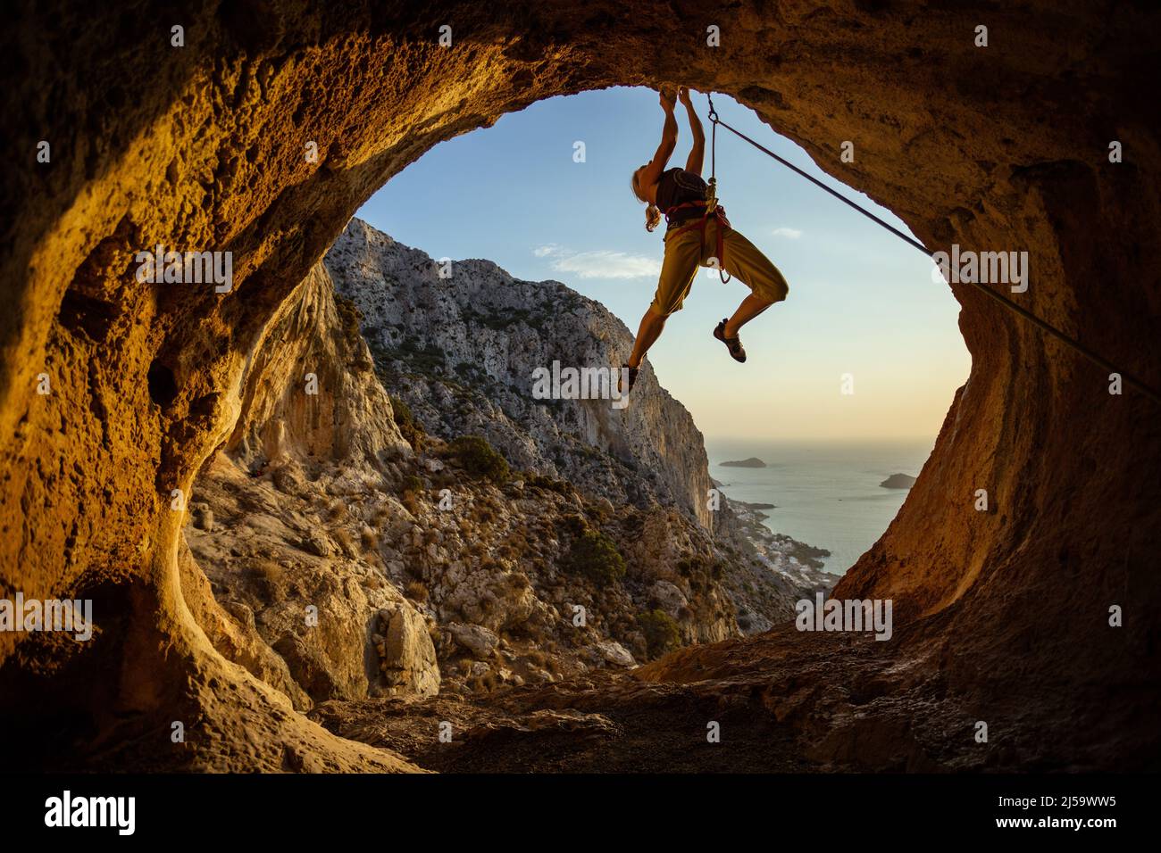 Giovane donna arrampicata impegnativo percorso in grotta Foto Stock