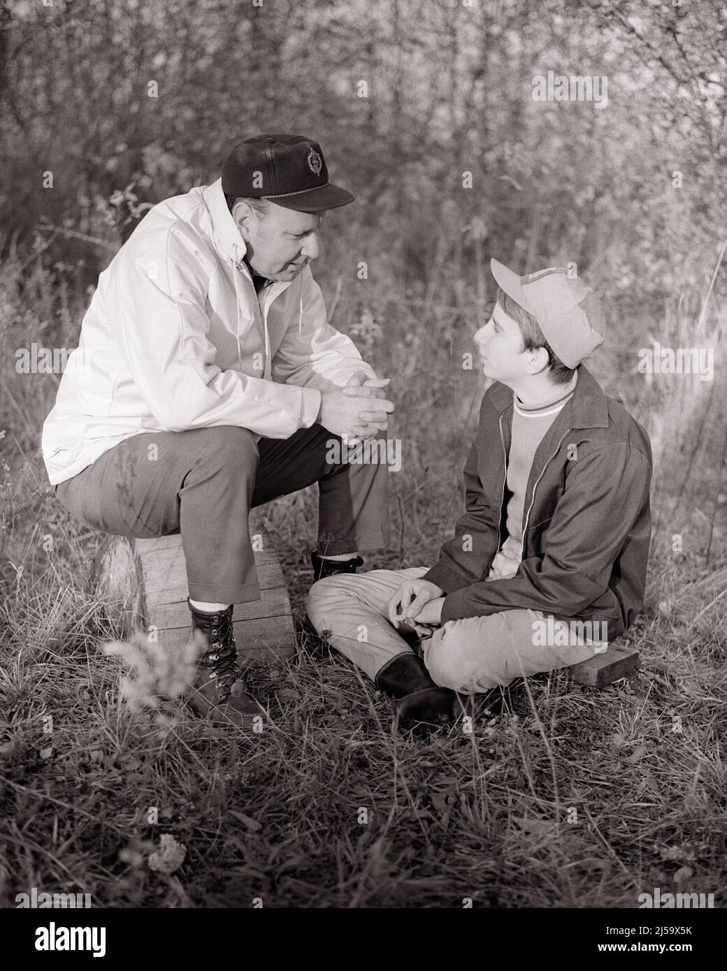 1960S UOMO PADRE E RAGAZZO FIGLIO SEDUTO ALL'APERTO IN AUTUNNO CAMPO AVENDO UNA CONVERSAZIONE SERIA ADULTO CHE PARLA E ASCOLTA - J12985 HAR001 HARS COPPIA LASCIA SUBURBANO VECCHIO TEMPO NOSTALGIA VECCHIA MODA CONVERSAZIONE 1 STILE GIOVANILE COMUNICAZIONE EQUILIBRIO LAVORO DI SQUADRA FIGLI FAMIGLIE GIOIA LIFESTYLE PARENTING RURALE HEALTHINESS HOME VITA NATURA PERSONE A TUTTA LUNGHEZZA PRENDERSI CURA DEI MASCHI ADOLESCENZA RAGAZZO SPIRITUALITÀ PADRI B&W FELICITÀ BENESSERE SCOPERTA E PAPÀ RICREAZIONE PADRE E FIGLIO AUTUNNO STAGIONE ORGOGLIO OPPORTUNITÀ AUTORITÀ CONNESSIONE CONCETTUALE TEENAGED PADRI E FIGLI MASCHIO LEGAME UOMO A MAN BASEBALL CAP GROWTH Foto Stock